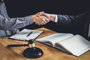 Handshake after good cooperation, Businessman Shaking hands with Professional male lawyer after discussing good deal of contract in courtroom.